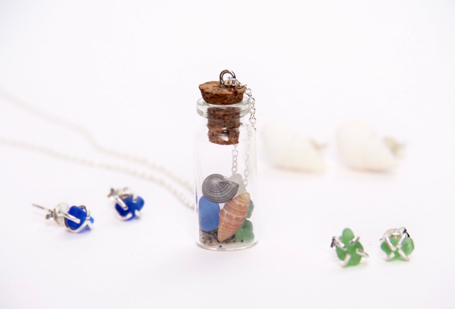 Glass bottle pendant necklace filled with colourful sea shells and beach sand, with sea glass and silver stud earrings. Handmade in Canada by Bridget Turner.