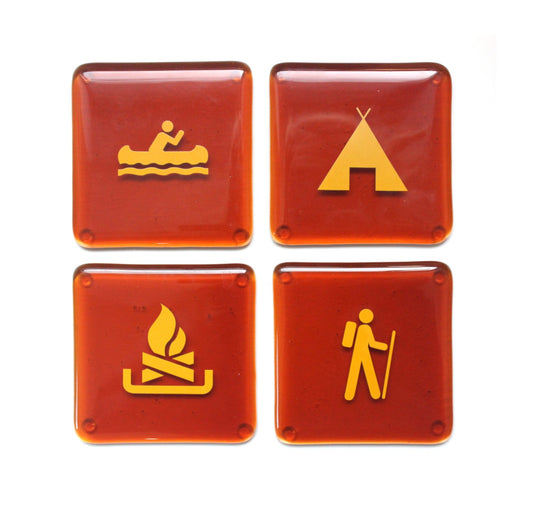 Made in Canada recycled beer bottle amber coloured set of four coasters with yellow camping symbols of a tent, hiker, canoe and fire.