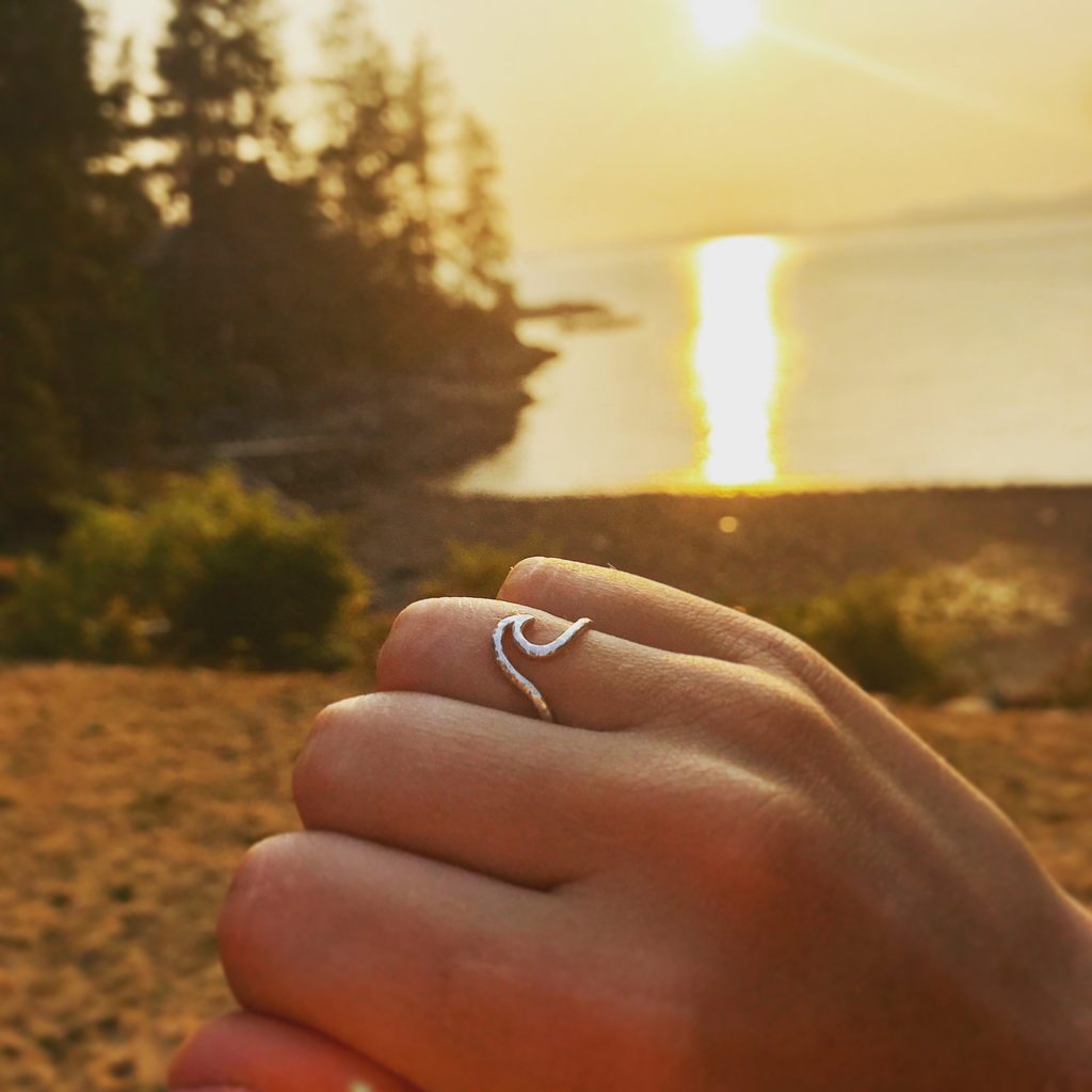 Made in Canada Justine Brooks silver textured wave ring with beach and sunset in the background.