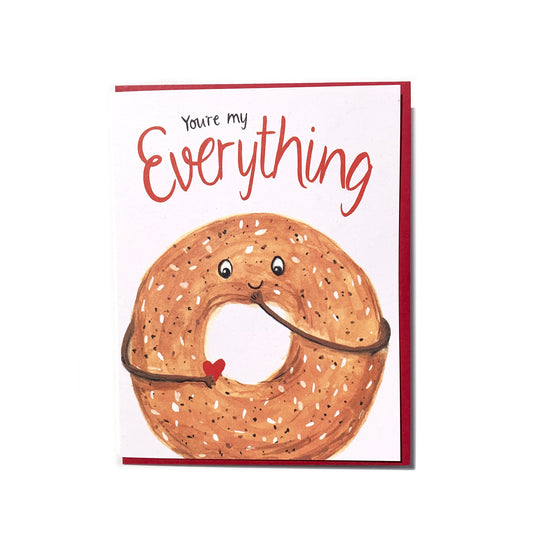 Canadian made love and friendship greeting card, with a silkscreen drawing of an everything bagel smiling and holding a heart. Caption reads: You're my everything