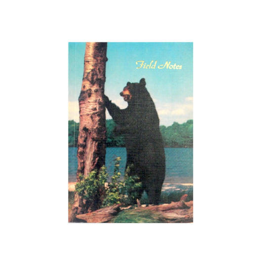 Canadian made notebook with a printed photograph of a black bear clawing a birch tree by a lake. 